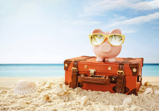Piggy bank wearing sunglasses resting on the tropical beach with copy space