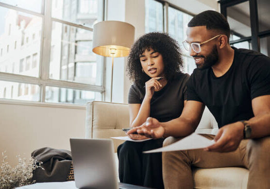 Finance, account and black couple with laptop on sofa doing online banking. Bills, budget and black man and woman with documents, paperwork and computer doing banking, payment and check bank account