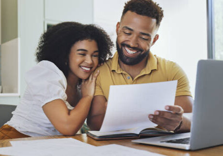 Couple celebrating financial freedom, using laptop, banking reports or statements to calculate budget, savings and finance. Happy debt free girlfriend and boyfriend with mortgage home loan approval